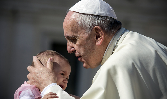 Pope Francis blesses crying child during a weekly ceremony in the Vatican City.